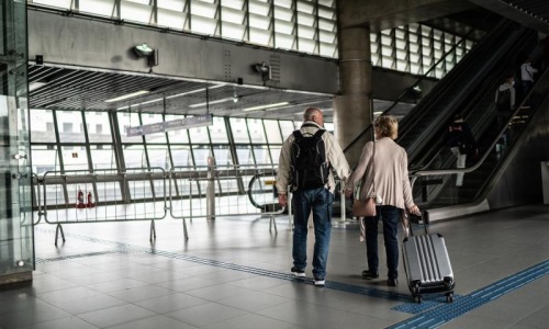 a man and a woman walking with luggage through an airport